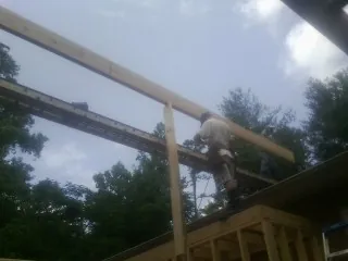 Carpenter setting a ridge beam over a new addition frame — Ice Dam Removal by Roofing Brothers in Trinity